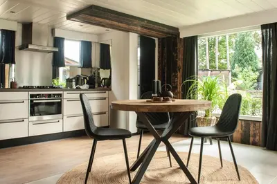 a kitchen with a wooden table and black chairs at Prachtige chalet Wabi Sabi aan het water! in Geel