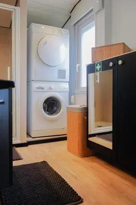 a laundry room with a washing machine and a window at Prachtige chalet Wabi Sabi aan het water! in Geel