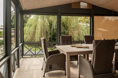 a dining room with a table and chairs on a balcony at Prachtige chalet Wabi Sabi aan het water! in Geel