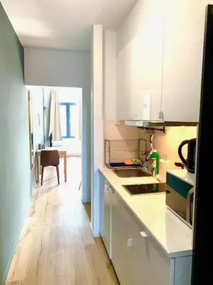 a kitchen with white cabinets and a wooden floor at Cozy Apartment in Antwerpen Centraal in Antwerp