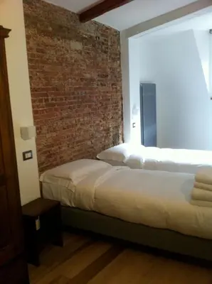 two beds in a room with a brick wall at L'Auberge de l'éclipse in Brussels