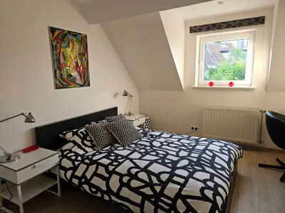a bedroom with a black and white bed and a window at Modern duplex with garden in Brussels