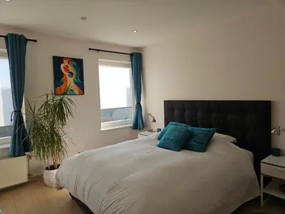 a bedroom with a large bed with blue pillows at Modern duplex with garden in Brussels