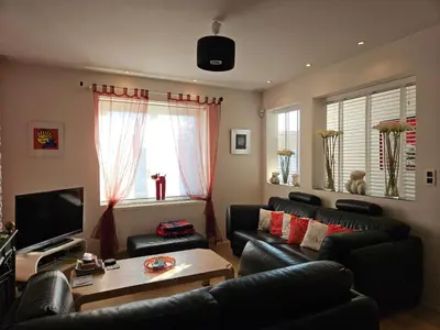 a living room with black leather furniture and a television at Modern duplex with garden in Brussels