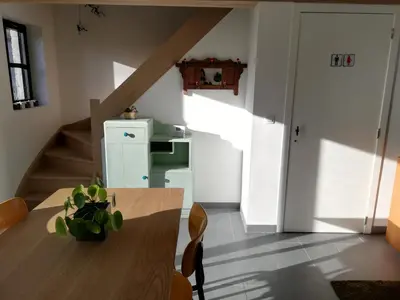 a dining room with a wooden table and a staircase at Noest in Destelbergen
