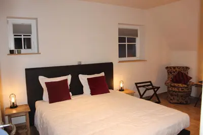 a bedroom with a large bed with two red pillows at B&B 't Mjeels Pierke in Meerle