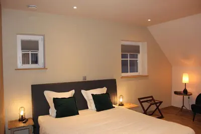 a bedroom with a large bed with two windows at B&B 't Mjeels Pierke in Meerle