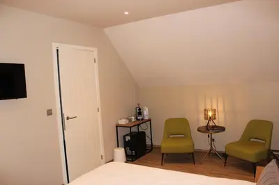 a bedroom with two chairs and a table and a bed at B&B 't Mjeels Pierke in Meerle