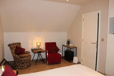 a bedroom with a bed and two chairs and a table at B&B 't Mjeels Pierke in Meerle