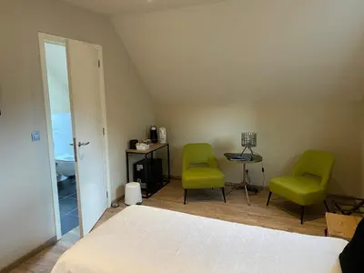 a bedroom with two green chairs and a bed at B&B 't Mjeels Pierke in Meerle