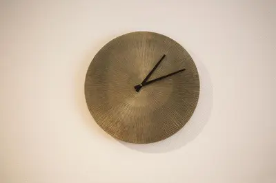 a wooden clock hanging on a wall at Center Design Residence in Brussels