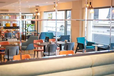 a restaurant with colorful chairs and tables and windows at B&B HOTEL Gent Centrum in Ghent