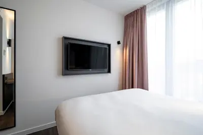 a bedroom with a bed and a flat screen tv at B&B HOTEL Gent Centrum in Ghent