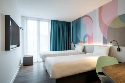 a hotel room with two beds and a tv at B&B HOTEL Gent Centrum in Ghent