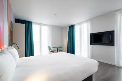 a hotel room with a white bed and a flat screen tv at B&B HOTEL Gent Centrum in Ghent