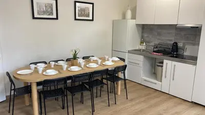 a kitchen with a wooden table with chairs and a kitchen with white appliances at Сarnot Apartments ZOO Area in Antwerp