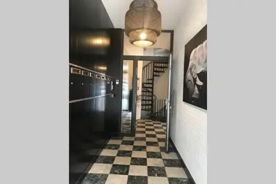 a hallway with a checkered floor and a light fixture at The Penthouse, oasis of light and inspiration in Antwerp