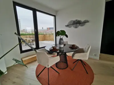 a living room with a table and chairs and a window at The Penthouse, oasis of light and inspiration in Antwerp