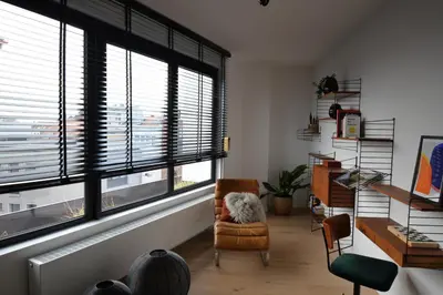 a living room with a chair and large windows at The Penthouse, oasis of light and inspiration in Antwerp
