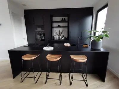 a kitchen with a black island with three bar stools at The Penthouse, oasis of light and inspiration in Antwerp