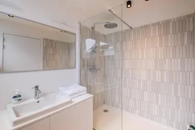 a white bathroom with a sink and a shower at Top Floor New Duplex Stunning View In Trendy St Gilles in Brussels