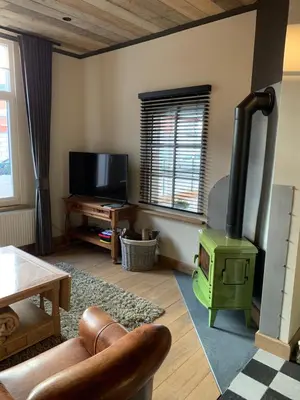 a living room with a wood stove and a tv at Vélo 94 in Geel