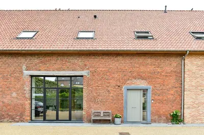 a red brick building with a white door and windows at B&B O Chocolat Cho in Sint-Pieters-Leeuw