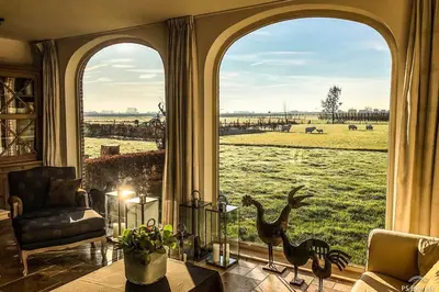 a room with a large window with a view of a field at Gastenhuis prachtige Historische Vierkant Hoeve in Broechem