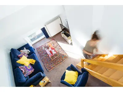a woman standing in a living room with a blue couch at B&B Place Jourdan in Brussels