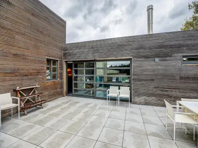 a patio with white chairs and a wooden wall at Apartment in Weelde with swimming pool in Weelde