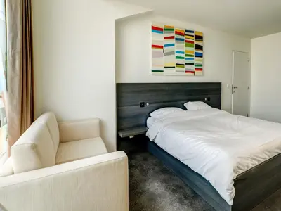 a bedroom with a bed and a chair and a painting at Apartment in Weelde with swimming pool in Weelde