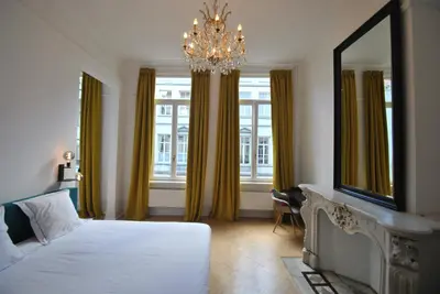 a bedroom with a bed and a mirror and a chandelier at Paulus41 in Antwerp
