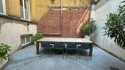 a wooden table and chairs in a courtyard with a brick wall at Paulus41 in Antwerp