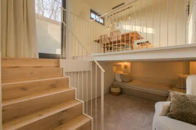a room with a staircase with a couch and a table at Logie Marie with hottub in the garden in Lembeke
