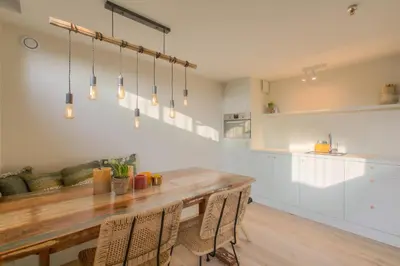 a kitchen and dining room with a wooden table and chairs at Logie Marie with hottub in the garden in Lembeke