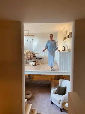 a man standing on a balcony in a living room at Logie Marie with hottub in the garden in Lembeke
