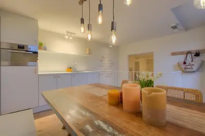 a kitchen with a wooden table with two candles on it at Logie Marie with hottub in the garden in Lembeke