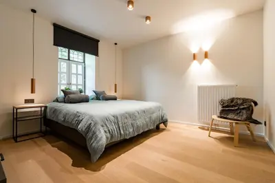 a bedroom with a bed and a chair and a window at B&B Weselo in Mol