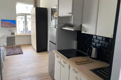 a kitchen with white cabinets and a black refrigerator at Magnifique Studio au 2ème étage, à proximité de la gare du midi! in Brussels