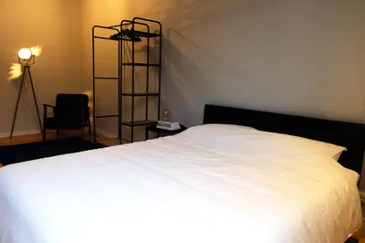 a bedroom with a white bed and a black shelf at Margareta Stay in Mechelen