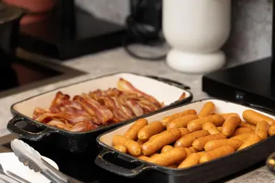 a table with a tray of sausages and a pan ofokedokedoked at Residence Inn by Marriott Brussels Airport in Diegem