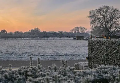 a snow covered field with a fence and a lake at Hotel Essenza in Puurs