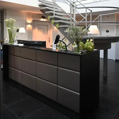 a reception desk with vases of flowers on it at Hotel Essenza in Puurs