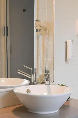 a bathroom with a white sink and a mirror at Hotel Essenza in Puurs