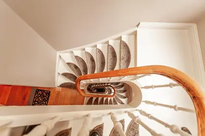 a spiral staircase in a house with a wooden rail at Luxury Suites Palace by Rikas Hotels in Antwerp