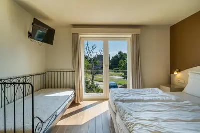 a bedroom with two beds and a large window at Logie Bloemenlust in Wetteren