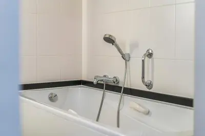 a bath tub with a shower in a bathroom at Logie Bloemenlust in Wetteren