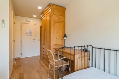 a bedroom with a bed and a wooden cabinet at Logie Bloemenlust in Wetteren