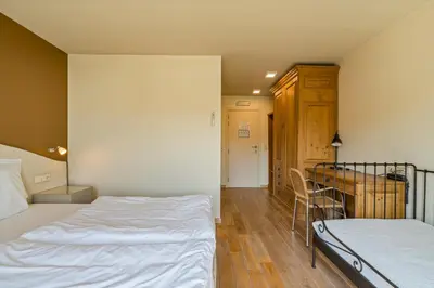 a bedroom with two beds and a chair in it at Logie Bloemenlust in Wetteren