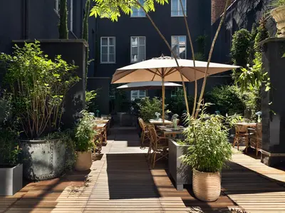 a patio with tables and an umbrella and potted plants at Juliana Hotel & Spa - Brussels Centre in Brussels